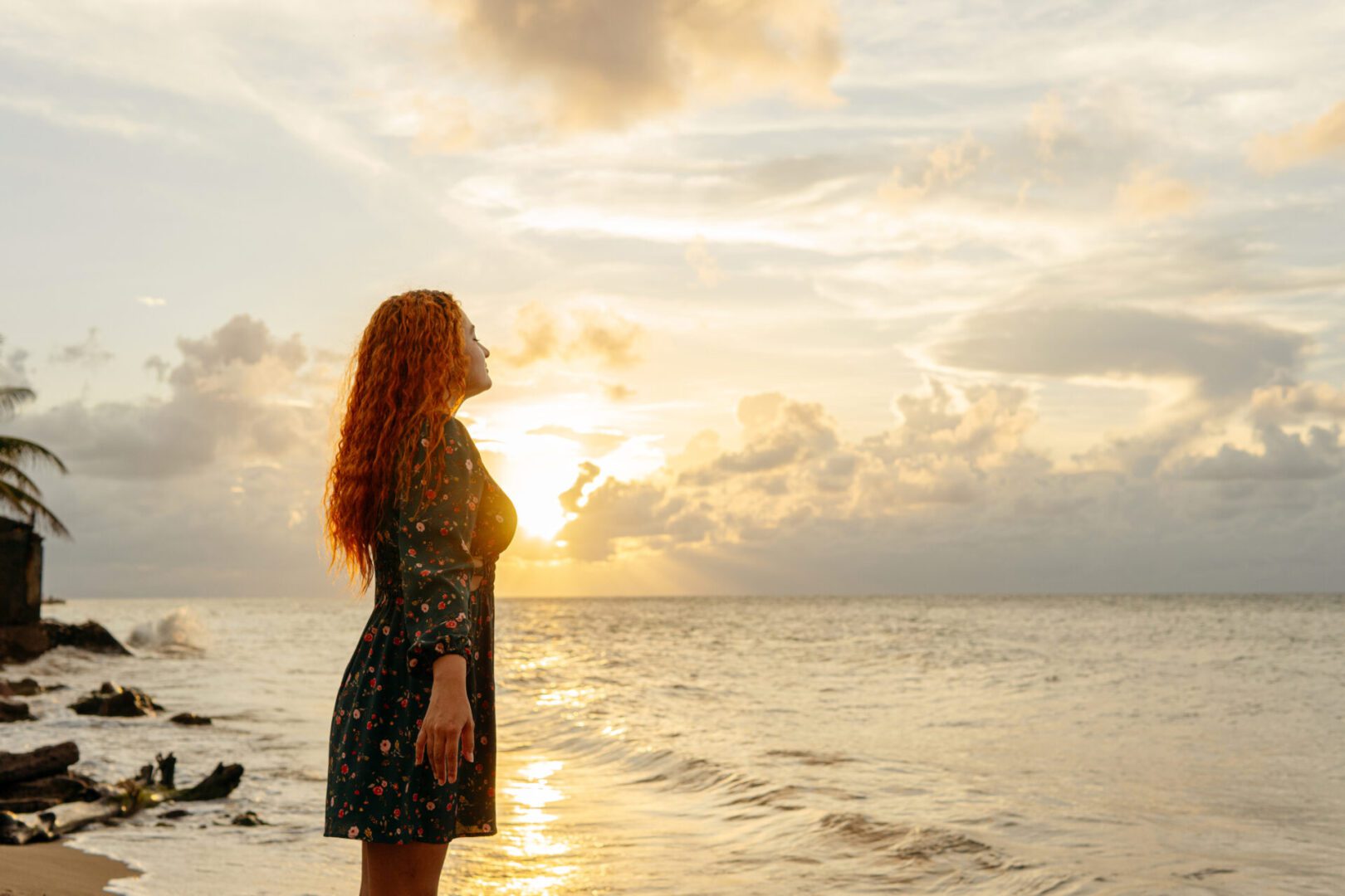 Woman standing on beach at sunset.